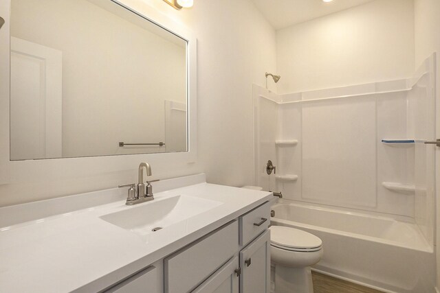 full bathroom with toilet, washtub / shower combination, wood finished floors, and vanity