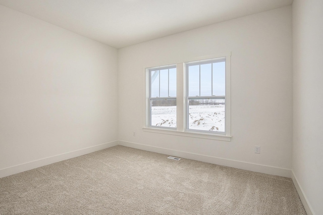 carpeted empty room featuring baseboards and visible vents