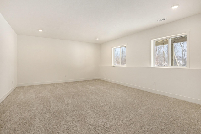 spare room featuring visible vents, light carpet, and baseboards