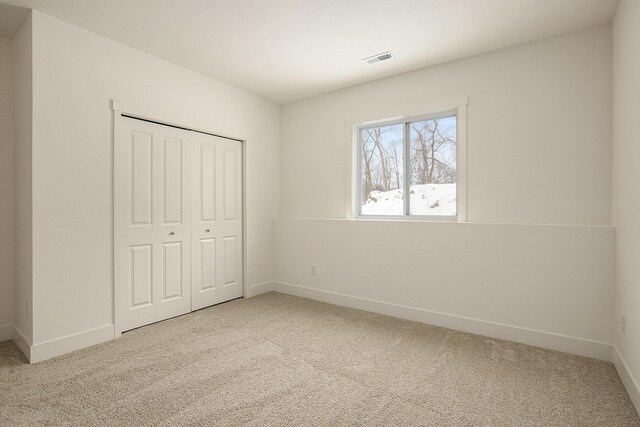 unfurnished bedroom featuring a closet, carpet flooring, visible vents, and baseboards