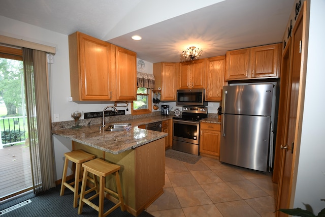 kitchen with kitchen peninsula, light tile patterned floors, sink, light stone countertops, and appliances with stainless steel finishes