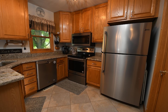 kitchen featuring appliances with stainless steel finishes, light stone counters, and light tile patterned floors