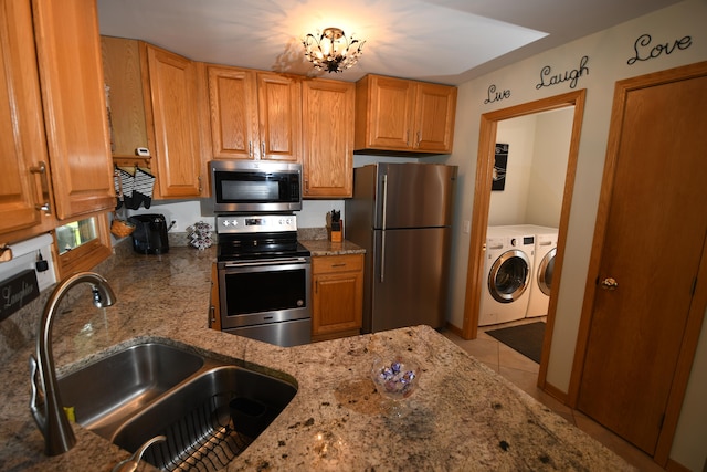 kitchen featuring light tile patterned floors, sink, light stone countertops, appliances with stainless steel finishes, and washer and dryer