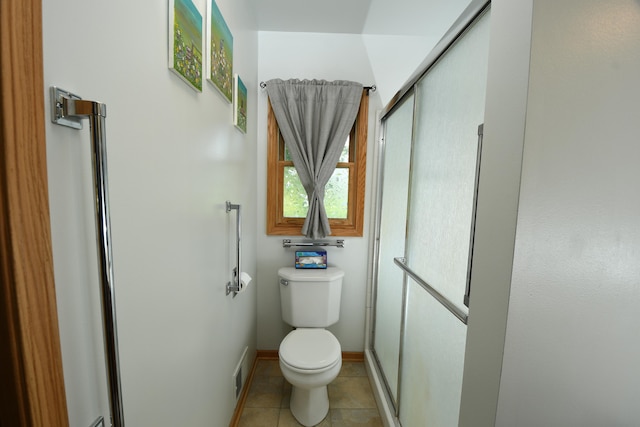 bathroom featuring toilet, an enclosed shower, and tile patterned floors