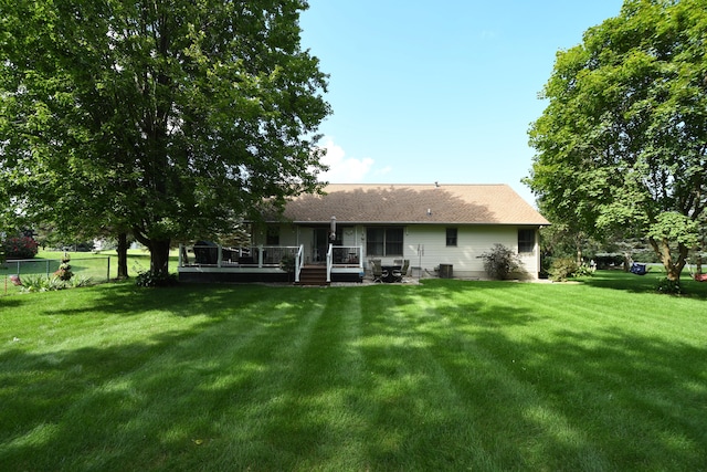 back of property with a wooden deck and a yard