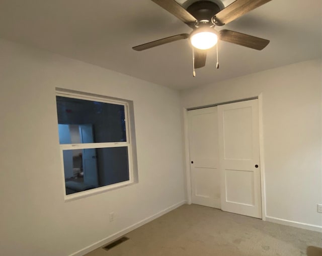 unfurnished bedroom with ceiling fan, light carpet, and a closet