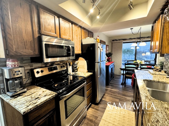 kitchen featuring light stone countertops, hanging light fixtures, stainless steel appliances, dark hardwood / wood-style flooring, and a notable chandelier