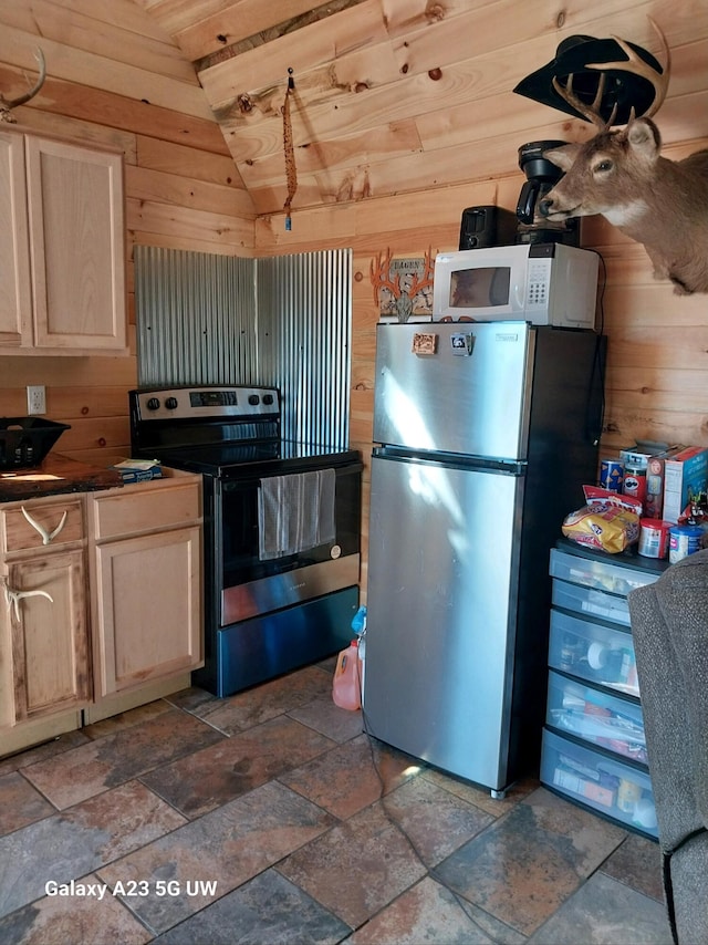 kitchen featuring stainless steel appliances, vaulted ceiling, and wood walls