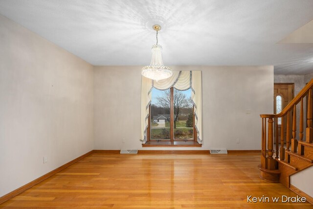 unfurnished dining area featuring a notable chandelier and light wood-type flooring