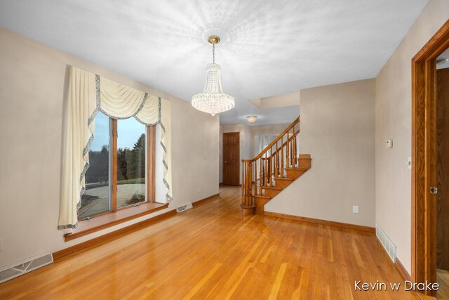 spare room with wood-type flooring and a notable chandelier