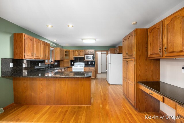 kitchen with white appliances, sink, light hardwood / wood-style flooring, tasteful backsplash, and kitchen peninsula