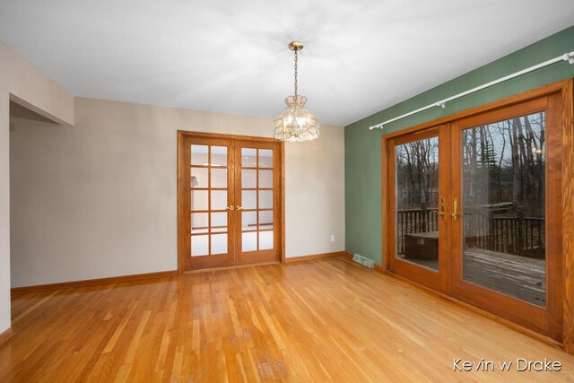 unfurnished room featuring french doors, a notable chandelier, and hardwood / wood-style floors