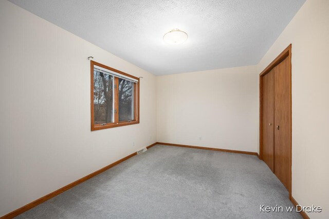 carpeted empty room with a textured ceiling