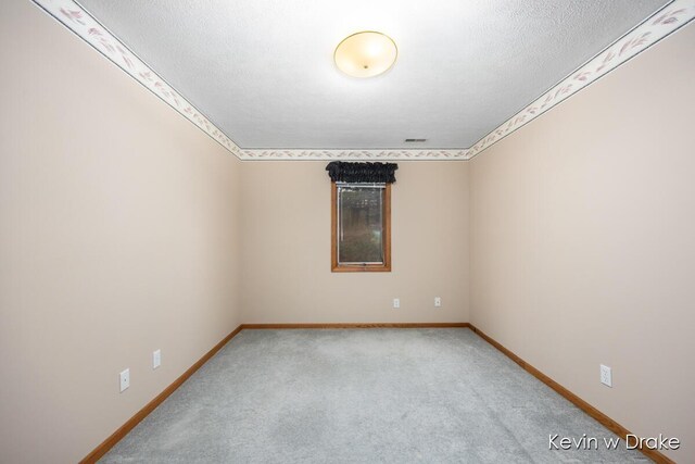 unfurnished room featuring light colored carpet and a textured ceiling