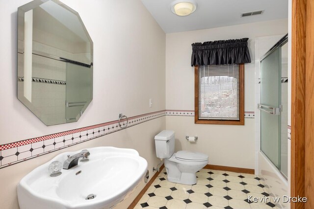 full bathroom featuring shower / bath combination with glass door, toilet, and sink