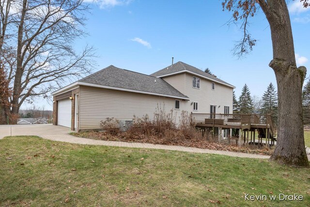 view of side of property featuring a lawn, a garage, and a deck