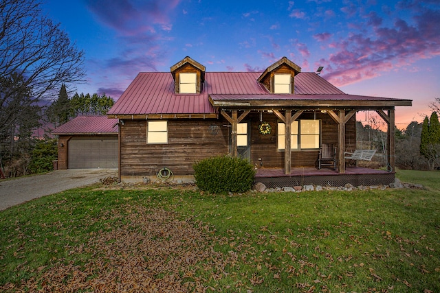 view of front of home with a lawn, covered porch, and a garage