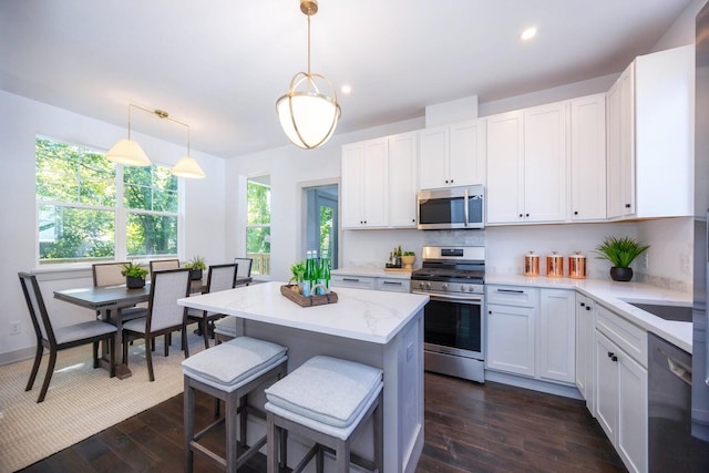 kitchen with dark hardwood / wood-style flooring, white cabinets, decorative light fixtures, and appliances with stainless steel finishes