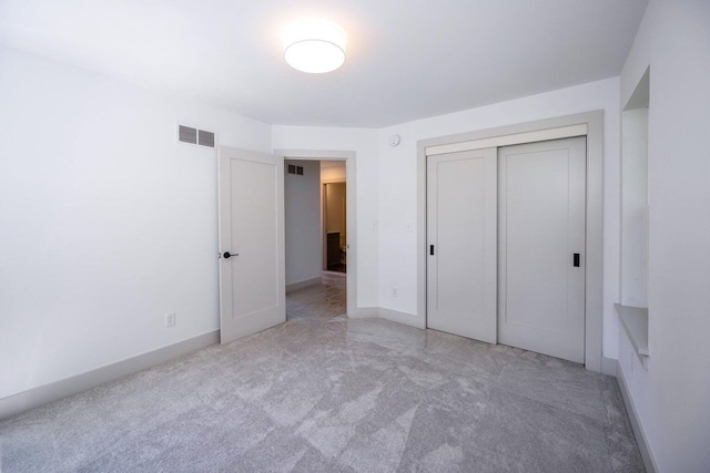 unfurnished bedroom featuring light carpet and a closet