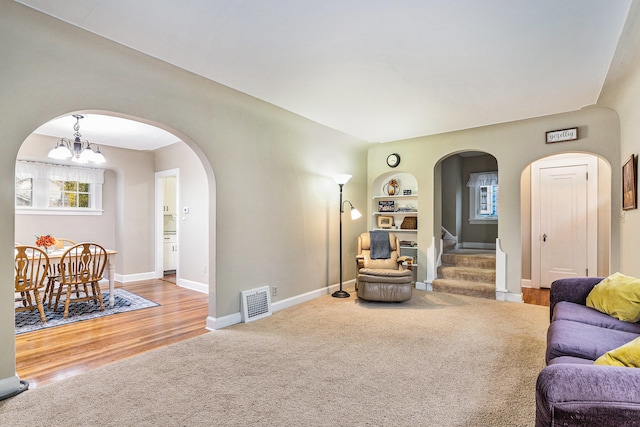 living room featuring hardwood / wood-style floors, built in shelves, and an inviting chandelier