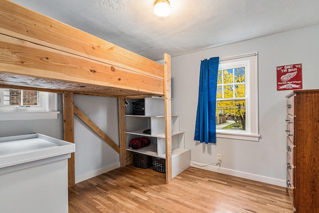 unfurnished bedroom with a textured ceiling, light hardwood / wood-style flooring, and multiple windows