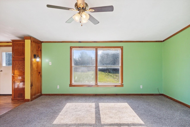 carpeted empty room with ceiling fan, a healthy amount of sunlight, and ornamental molding