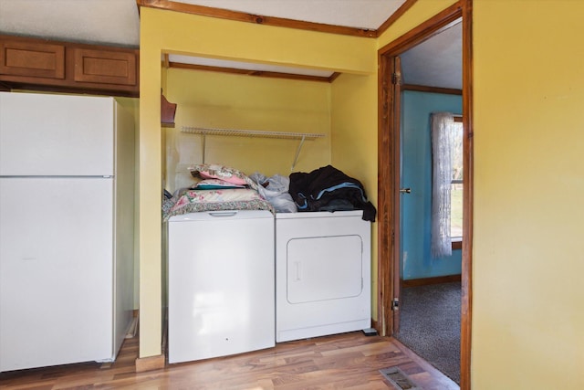 clothes washing area with independent washer and dryer, hardwood / wood-style flooring, and crown molding