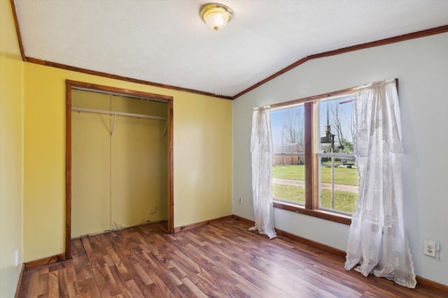 unfurnished bedroom featuring a closet, crown molding, wood-type flooring, and lofted ceiling