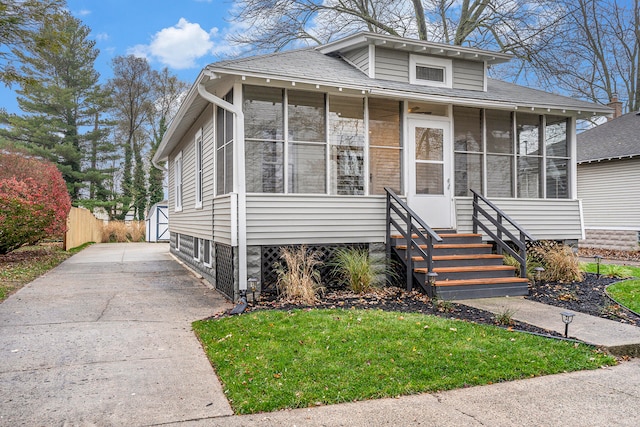 view of front of home with a sunroom, a front lawn, an outdoor structure, and a garage