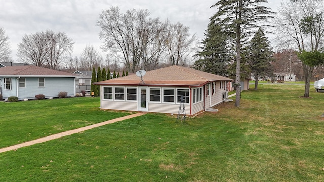 rear view of property featuring a yard and a sunroom