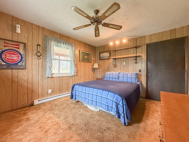 carpeted bedroom featuring baseboard heating, ceiling fan, a textured ceiling, and wood walls