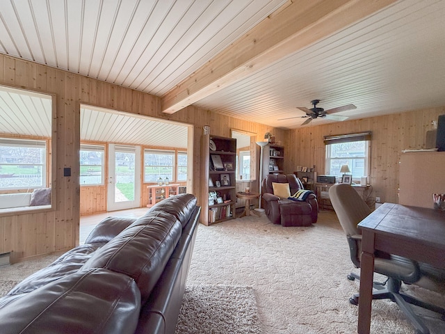 living room featuring carpet, beam ceiling, ceiling fan, and wooden walls