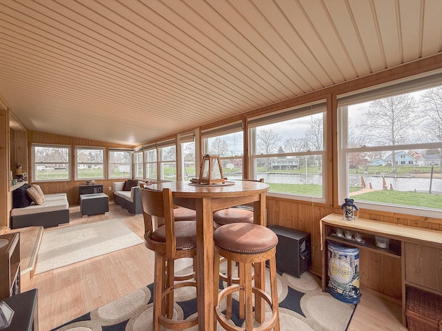 sunroom / solarium featuring wooden ceiling, a water view, plenty of natural light, and lofted ceiling