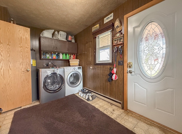 laundry room featuring washing machine and clothes dryer, a baseboard radiator, wood walls, and a textured ceiling