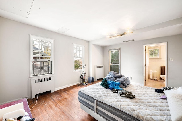 bedroom with radiator, wood-type flooring, and ensuite bathroom