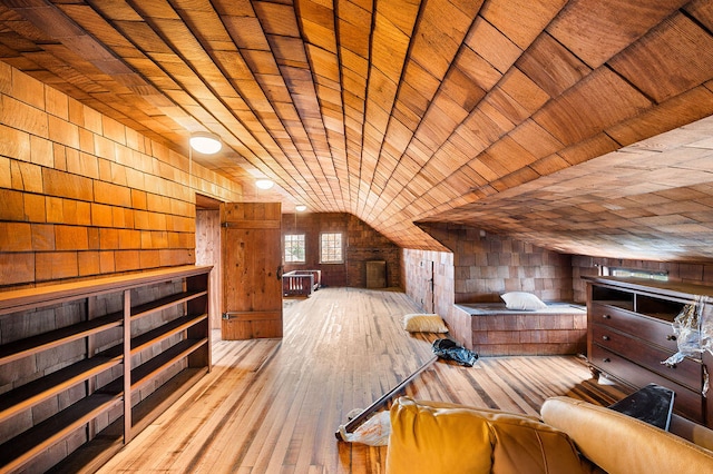 additional living space with wood walls, wood ceiling, light hardwood / wood-style flooring, and vaulted ceiling