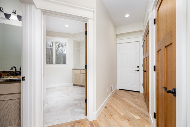 hall with light hardwood / wood-style floors and sink