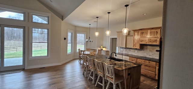 kitchen featuring a kitchen breakfast bar, dark stone counters, vaulted ceiling, decorative backsplash, and a kitchen island