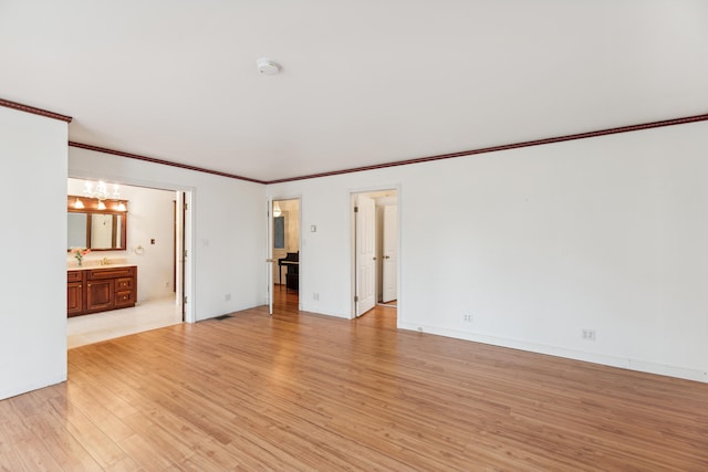 unfurnished bedroom featuring ensuite bathroom, ornamental molding, and light wood-type flooring