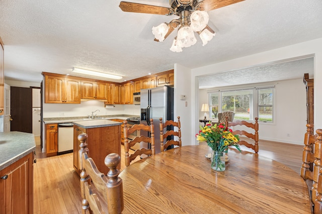 dining room with ceiling fan, sink, a textured ceiling, and light wood-type flooring