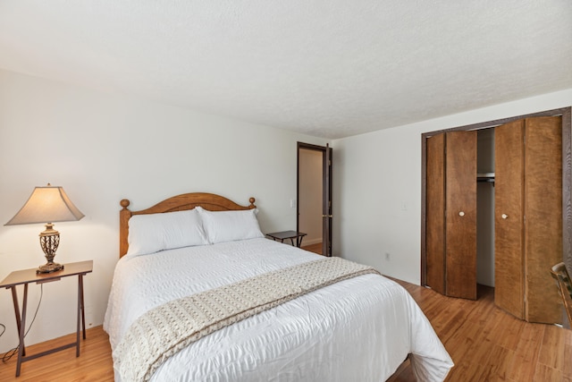 bedroom with a closet, a textured ceiling, and light wood-type flooring