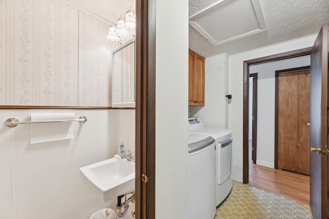 laundry room with cabinets, a textured ceiling, sink, separate washer and dryer, and light hardwood / wood-style flooring