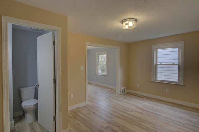 unfurnished room featuring a textured ceiling and light wood-type flooring