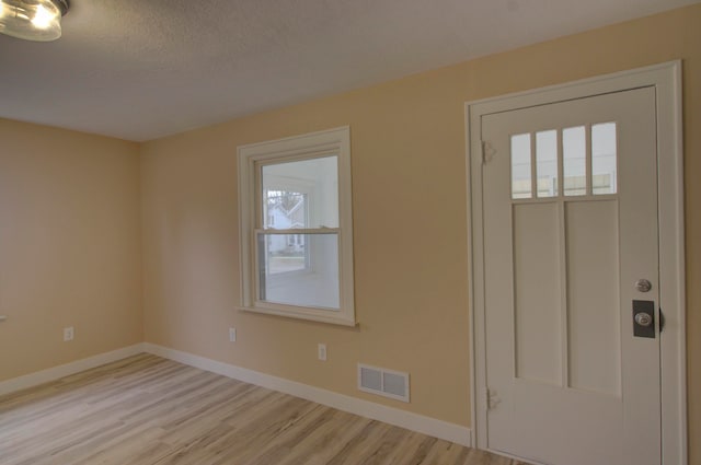 foyer entrance featuring light hardwood / wood-style flooring and a textured ceiling