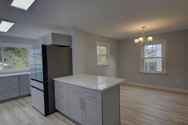 kitchen with gray cabinets, a chandelier, pendant lighting, and light hardwood / wood-style flooring