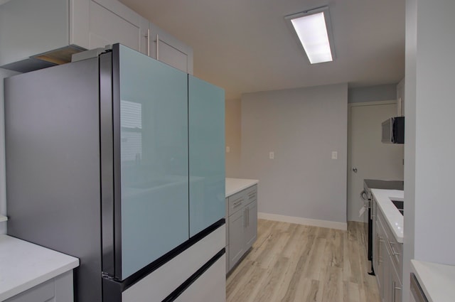 kitchen featuring stainless steel refrigerator, white cabinetry, and light hardwood / wood-style flooring