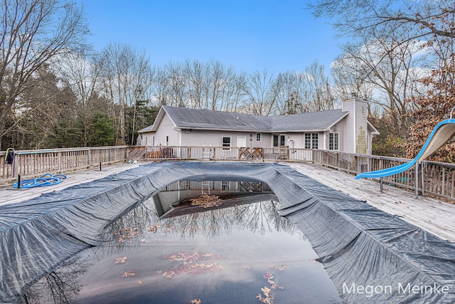 view of swimming pool featuring a water slide and a wooden deck