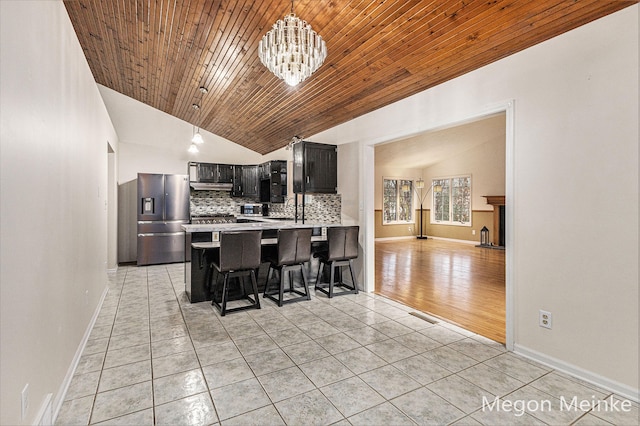 kitchen with vaulted ceiling, kitchen peninsula, wooden ceiling, a kitchen breakfast bar, and stainless steel fridge