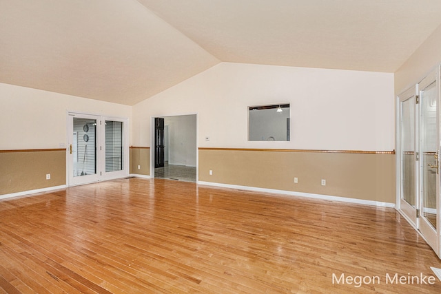 spare room with light wood-type flooring and vaulted ceiling