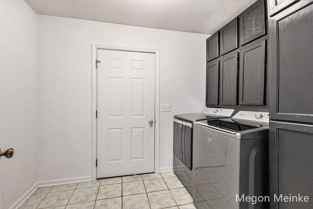 clothes washing area with cabinets, washing machine and clothes dryer, light tile patterned floors, and a textured ceiling